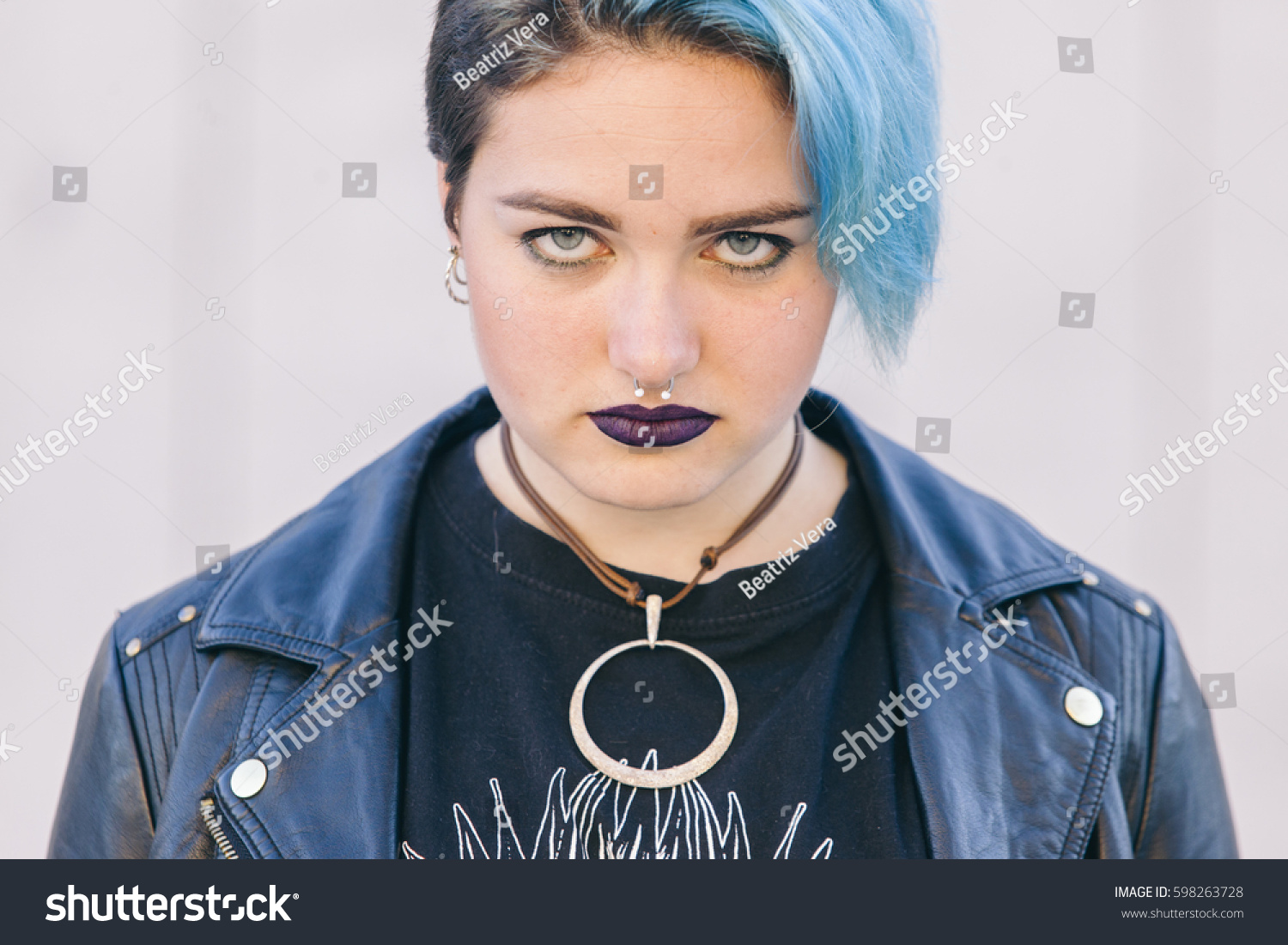 stock-photo-close-up-of-a-teen-punk-woman-with-a-nose-piercing-dyed-blue-hair-and-dark-lips-isolated-on-the-598263728.jpg
