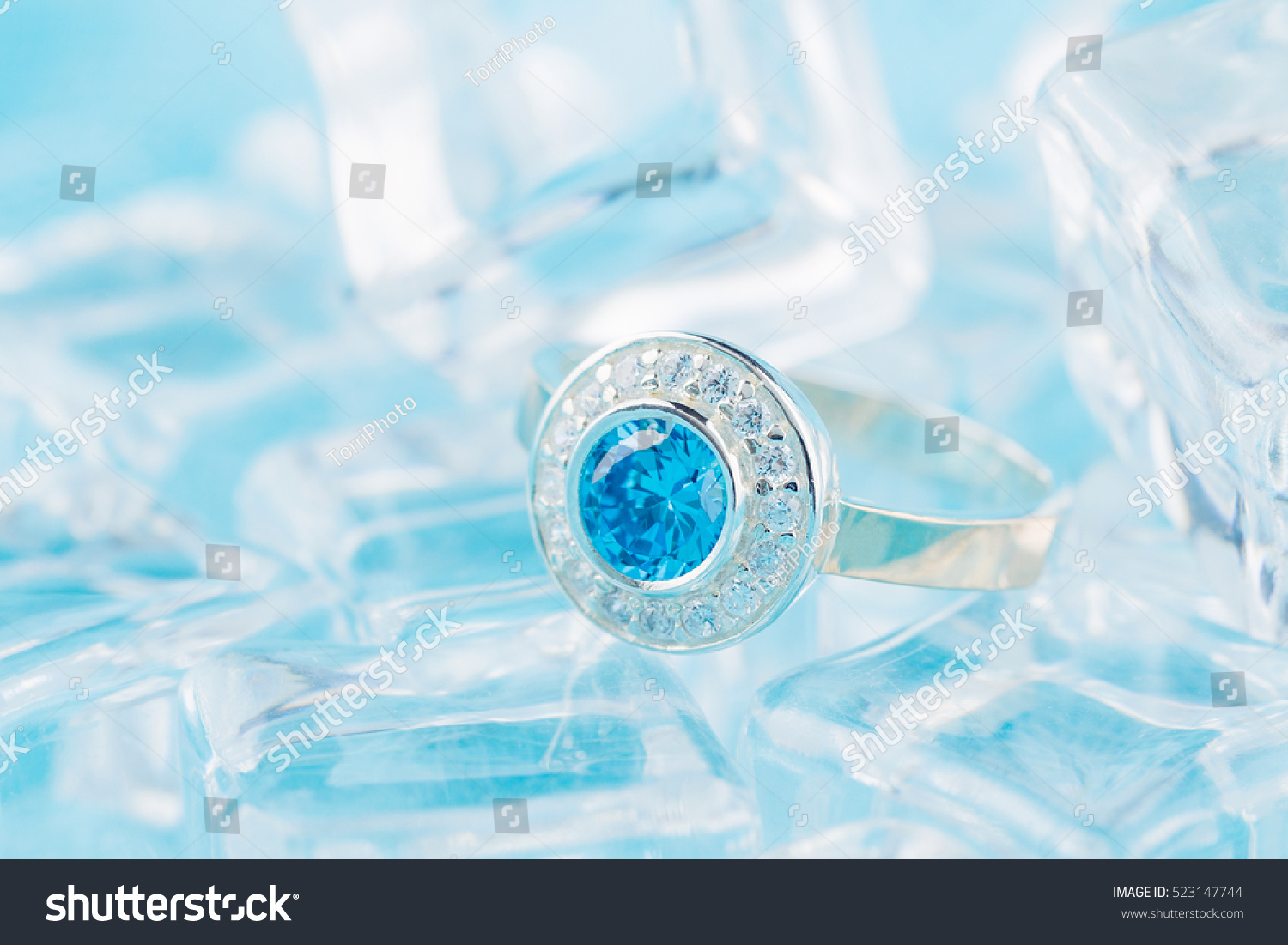 https://www.shutterstock.com/pic-523147744/stock-photo-close-up-silver-ring-with-zircon-and-expensive-blue-gemstone-still-life-on-ice-blue-background.html