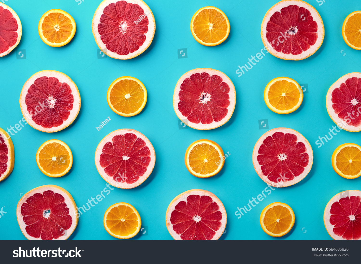 青の背景に新鮮なオレンジとグレープフルーツのスライスのカラフルなフルーツパターン 平面図から の写真素材 今すぐ編集