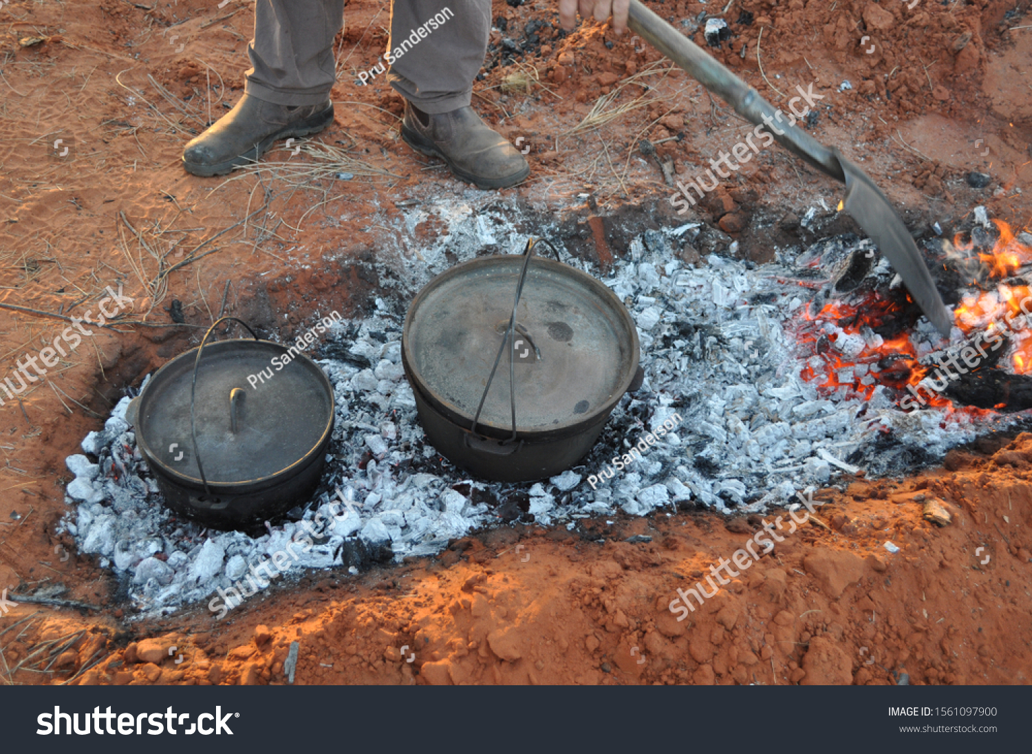 Cooking dinner in camp (Dutch) ovens over hot coals in the red sand of the Australian outback