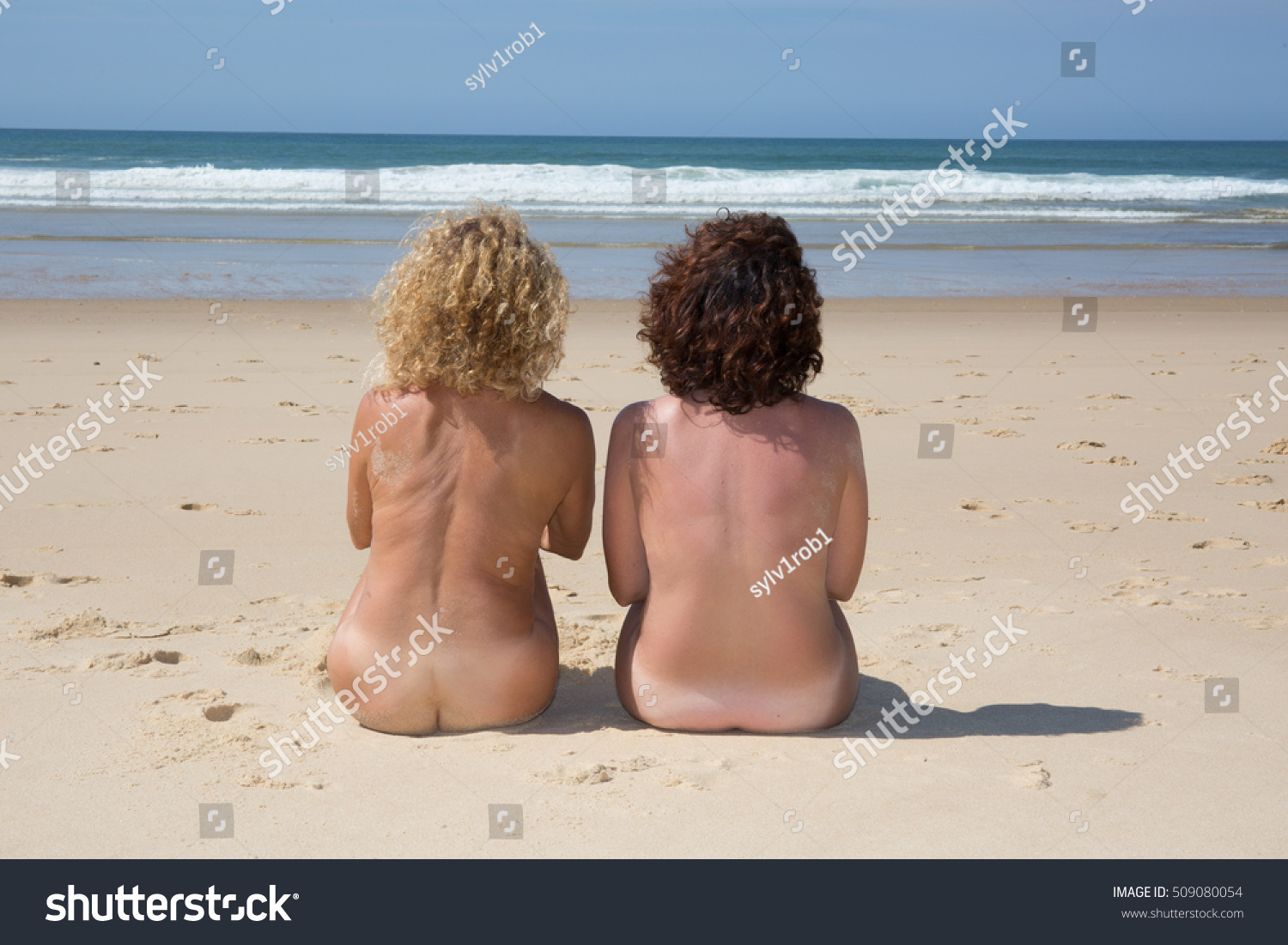 Two alluring women are relaxing on the nudist beach