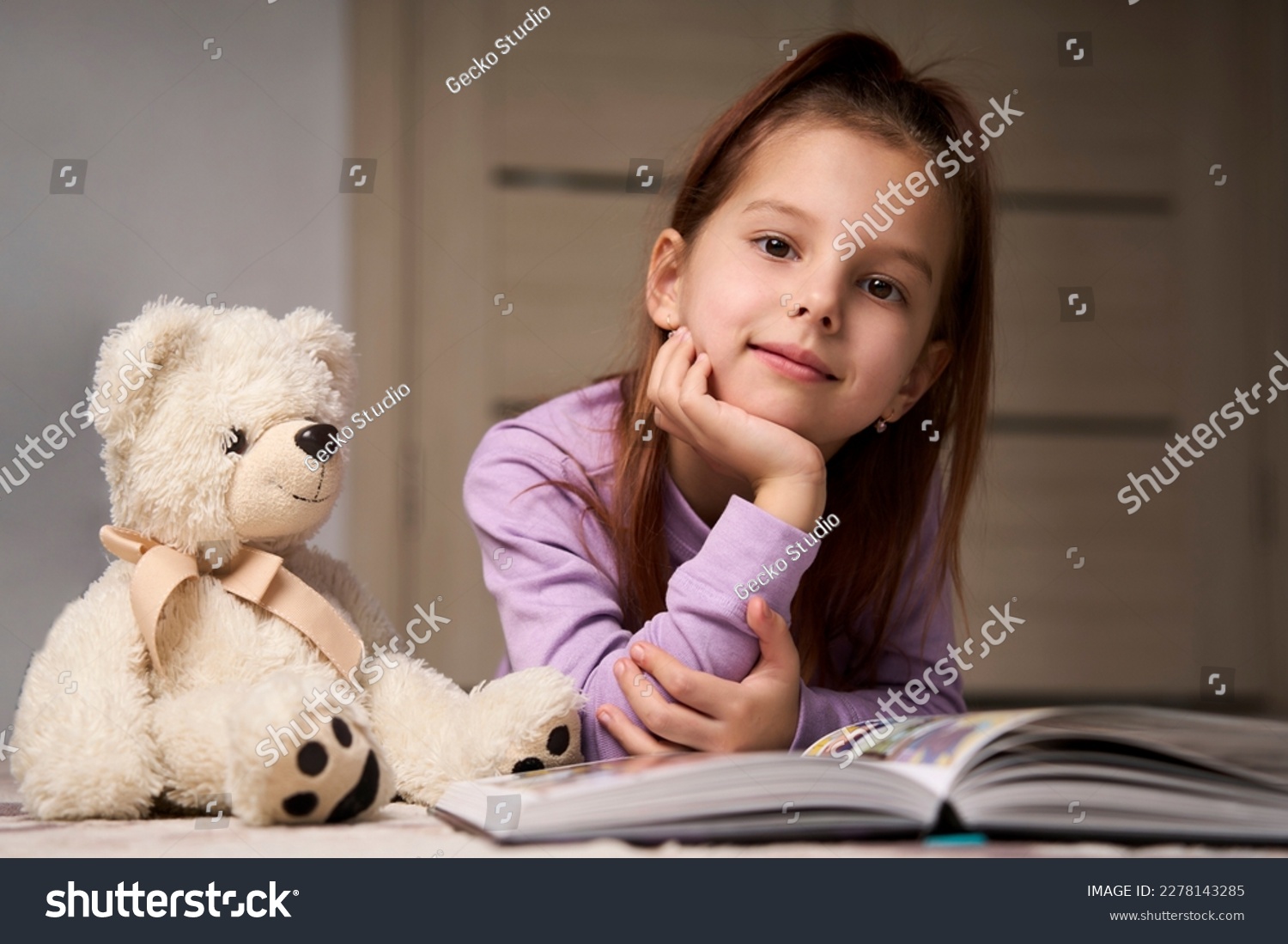 Cute girl lying on the floor and reading a book. Child girl reading ...