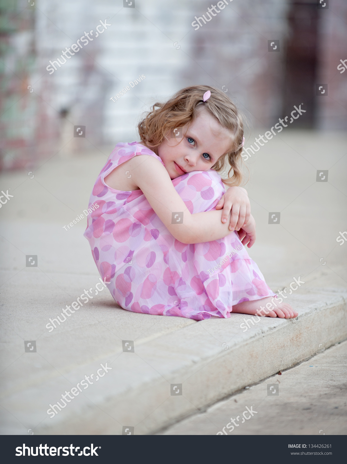 Cute Little Barefoot Girl In Pink Dress Sitting On Curb Hugging Her ...