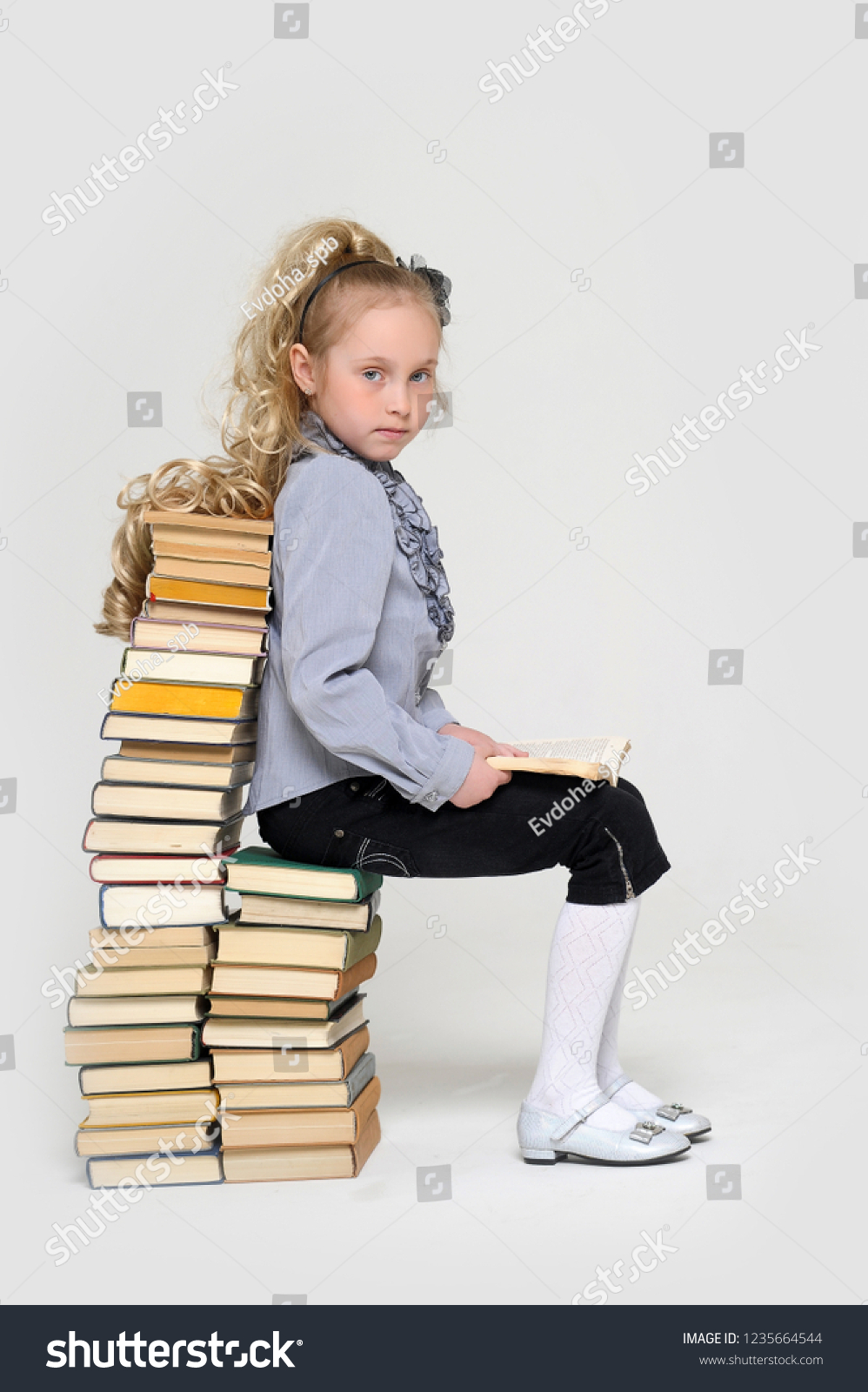 Little Girl Sitting On A Pile Of Stacked Logs In The Park Stock Image