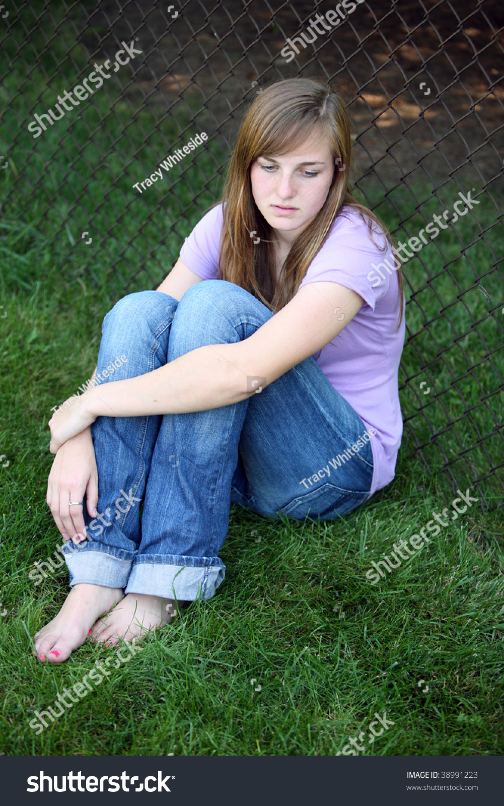 Depressed Teen Girl Sitting Against Fence In Grass Stock Photo 38991223 ...