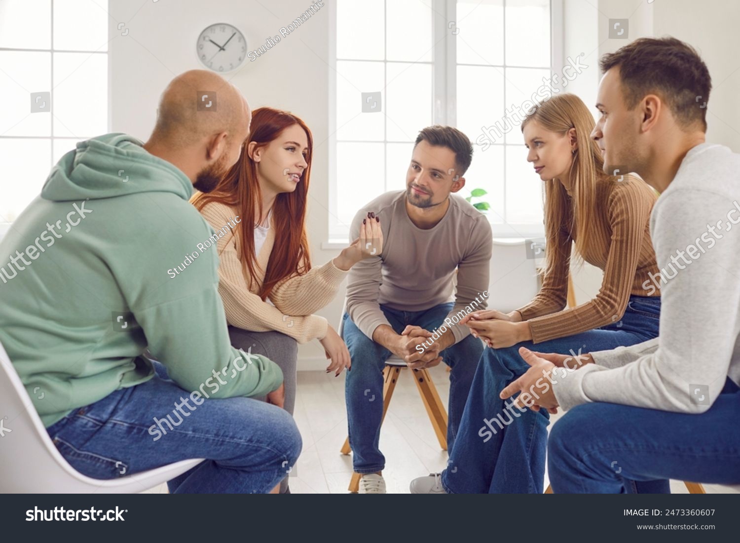 A group of people are sitting in a circle talking to each other.