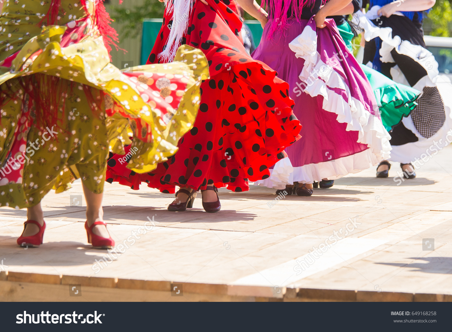 Feet of flamenco dancers, performing on a wooden stage in summer city festival