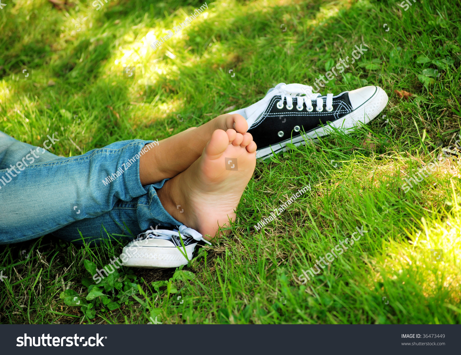 Feet Of The Girl Teenager And Gym Shoes On A Green Grass Of A Lawn In ...