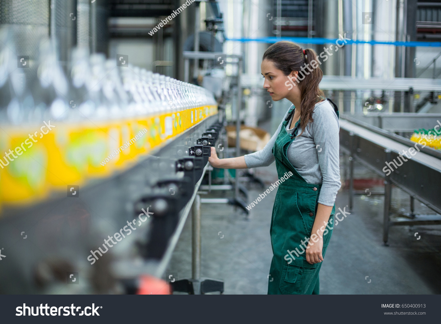 飲料製造工場で生産ラインを点検する女性の工場労働者 の写真素材 今すぐ編集