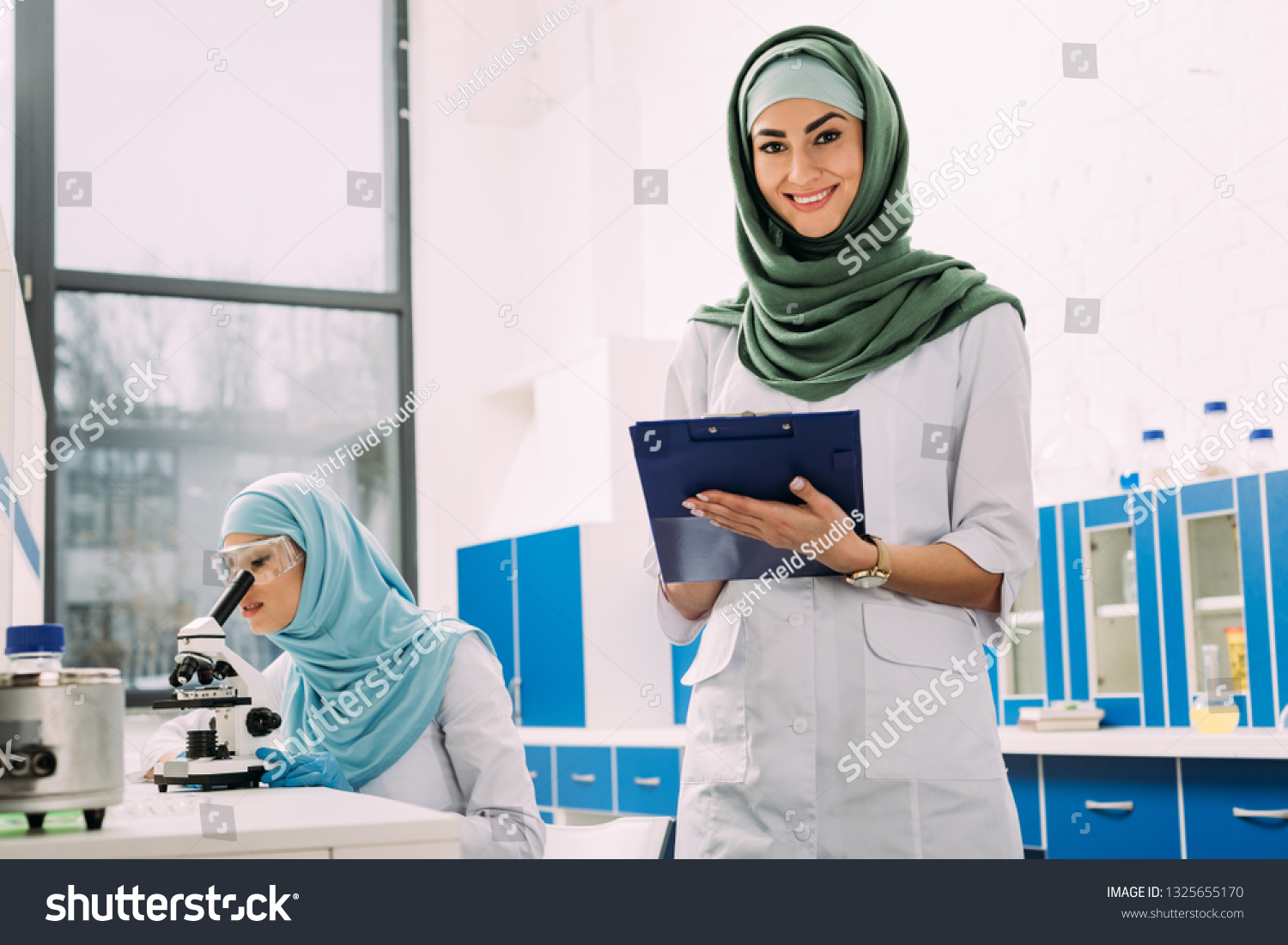 Female Muslim Scientists Using Microscope Clipboard Stock Photo ...