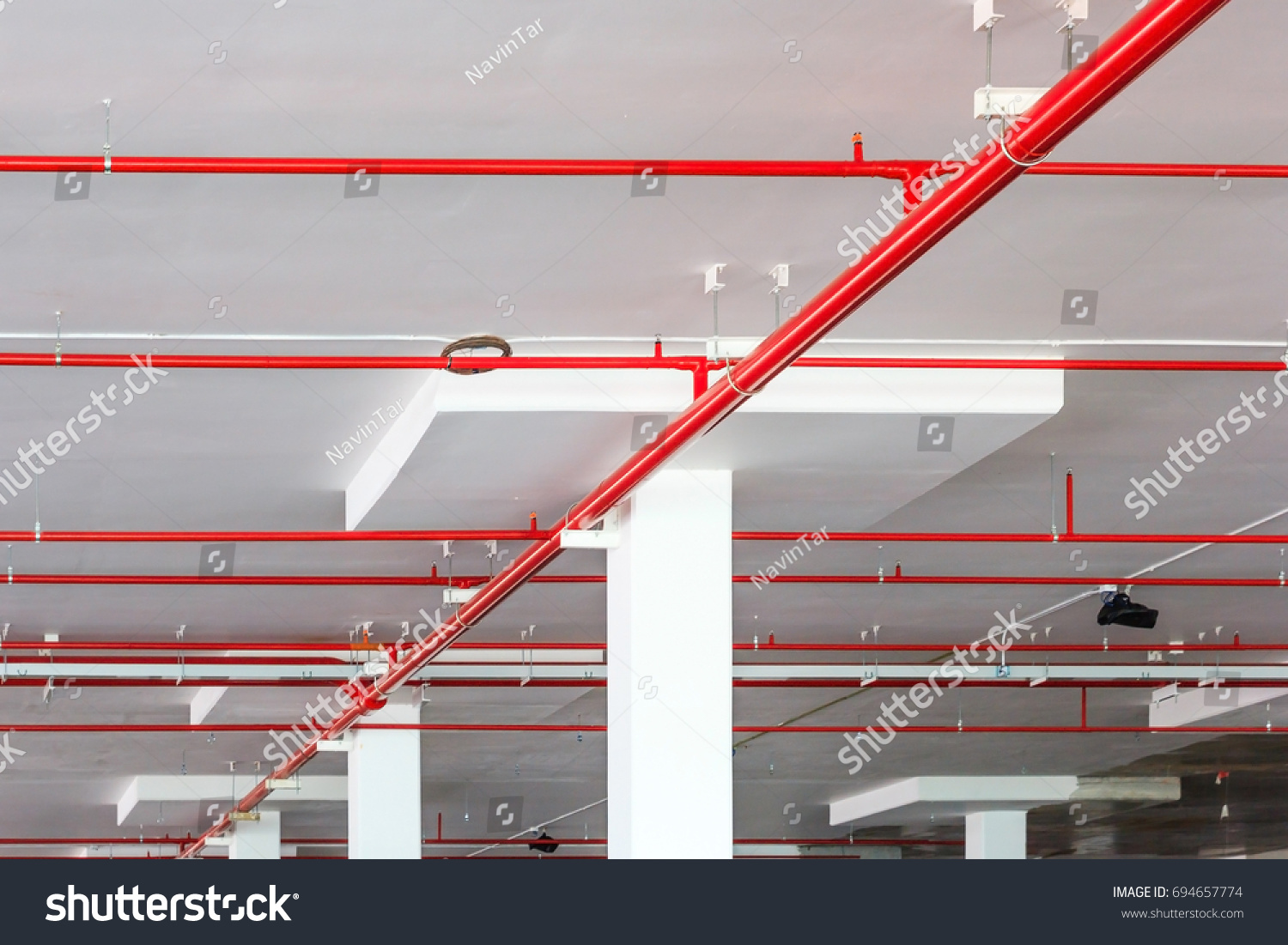 stock photo fire sprinkler system with red pipes is placed to hanging from the ceiling inside of an unfinished 694657774