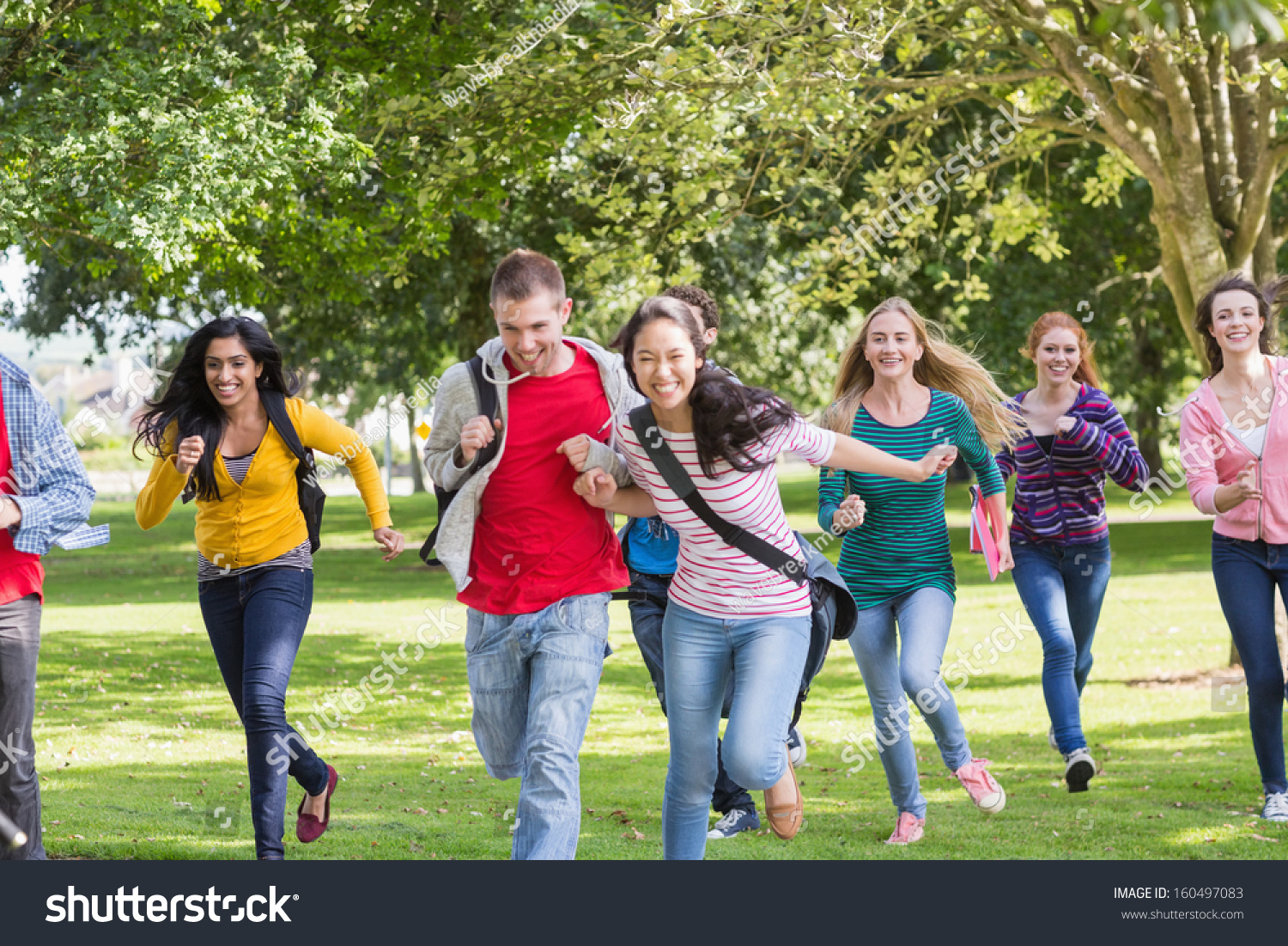 Full Length Of A Group Of College Students Running In The Park Stock ...