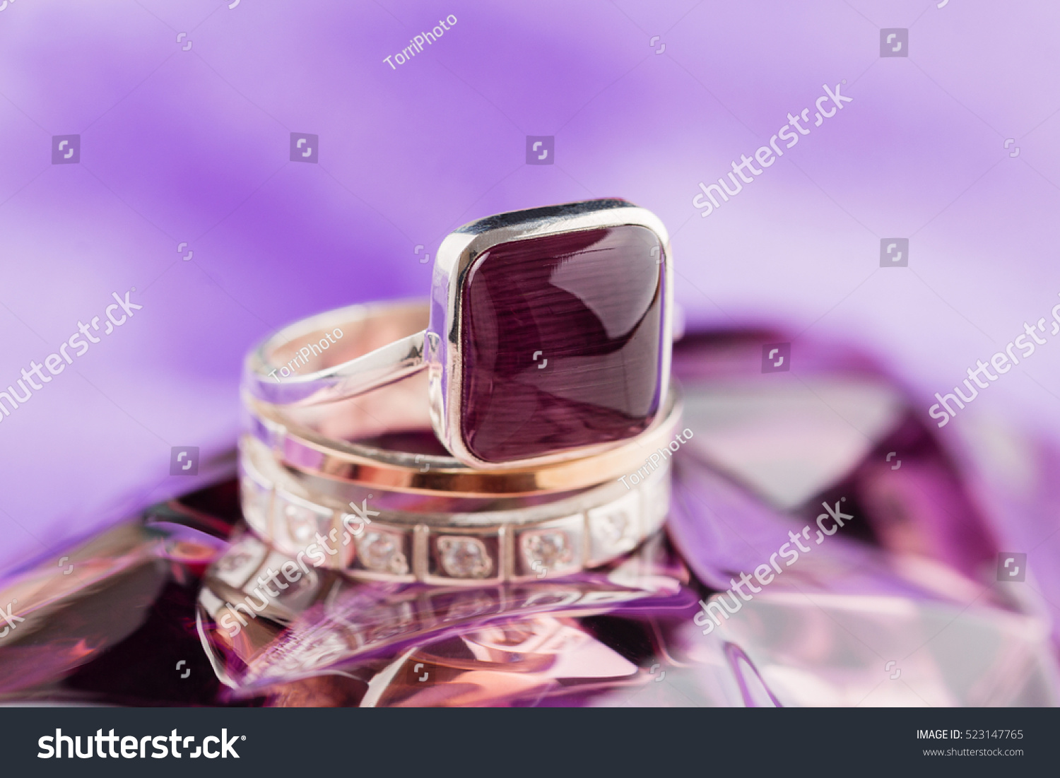 https://www.shutterstock.com/pic-523147765/stock-photo-gold-ring-square-shaped-with-purple-gemstones-on-violet-background.html