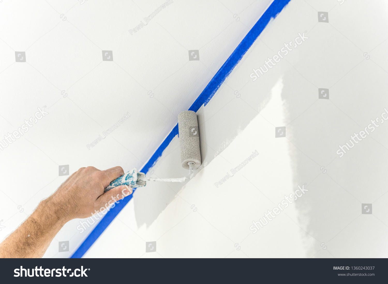 Stock Photo Hand Painting Wall With Roll In Grey Color Using Blue Paint Tape 1360243037 