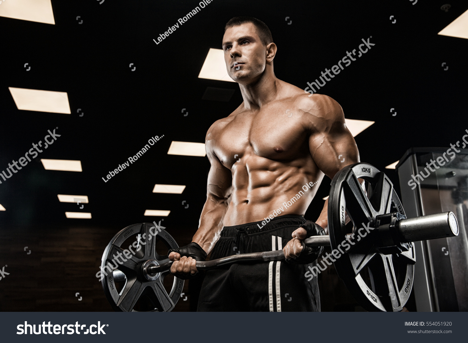 Handsome man with big muscles, posing at the camera in the gym