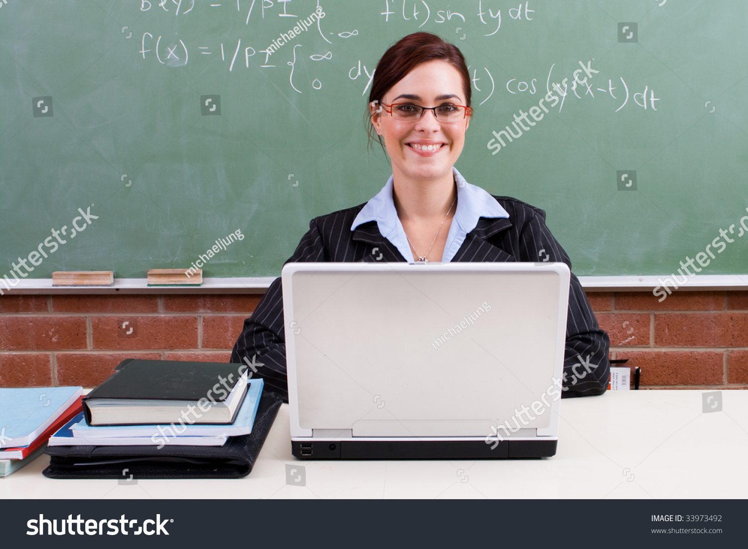 Happy Attractive Female Teacher Sitting In Front Of Blackboard Stock ...