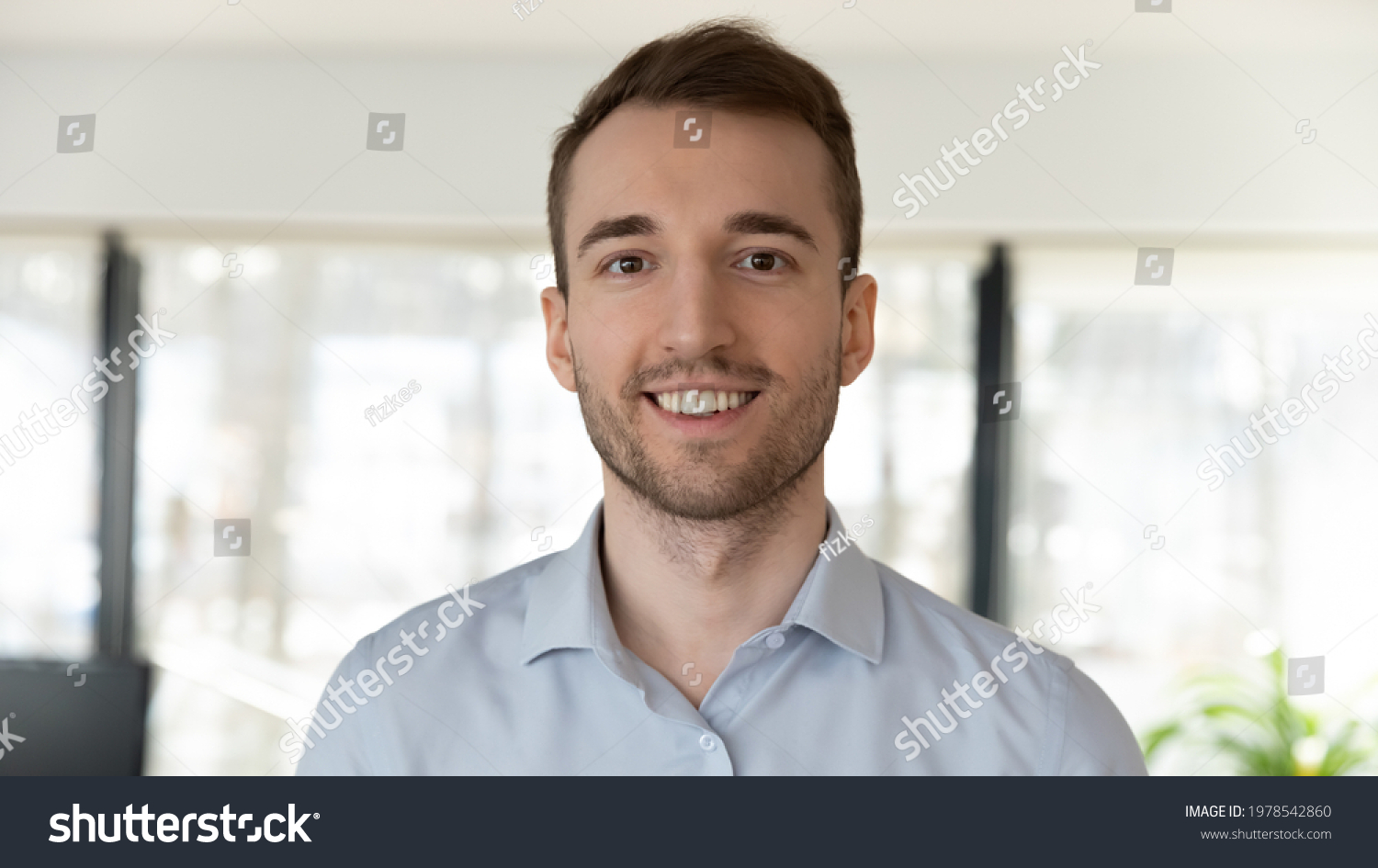 A man with a beard is smiling and looking at the camera.