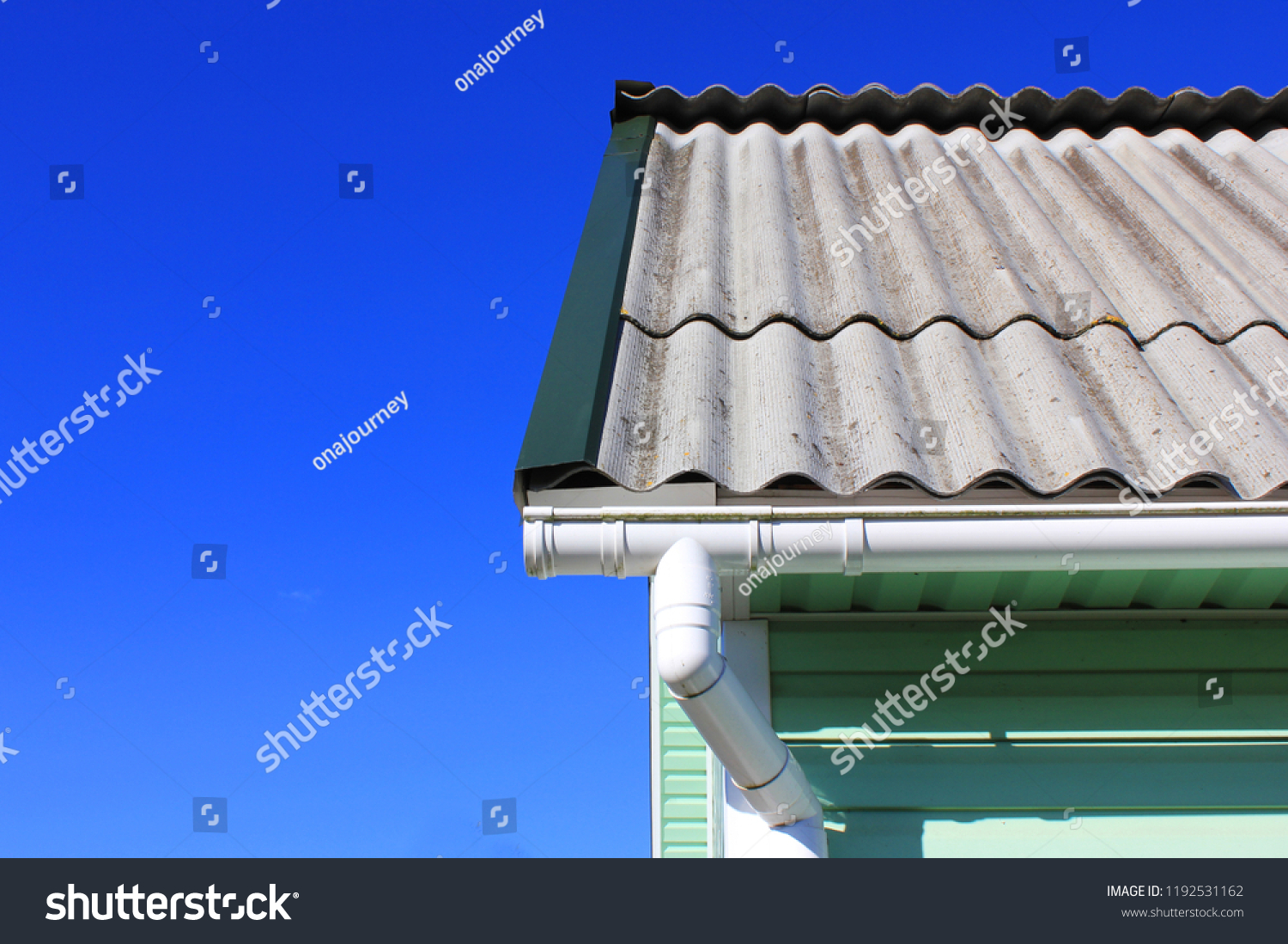 House corner with gutter roof top tiles drainage system and azure wall detail on