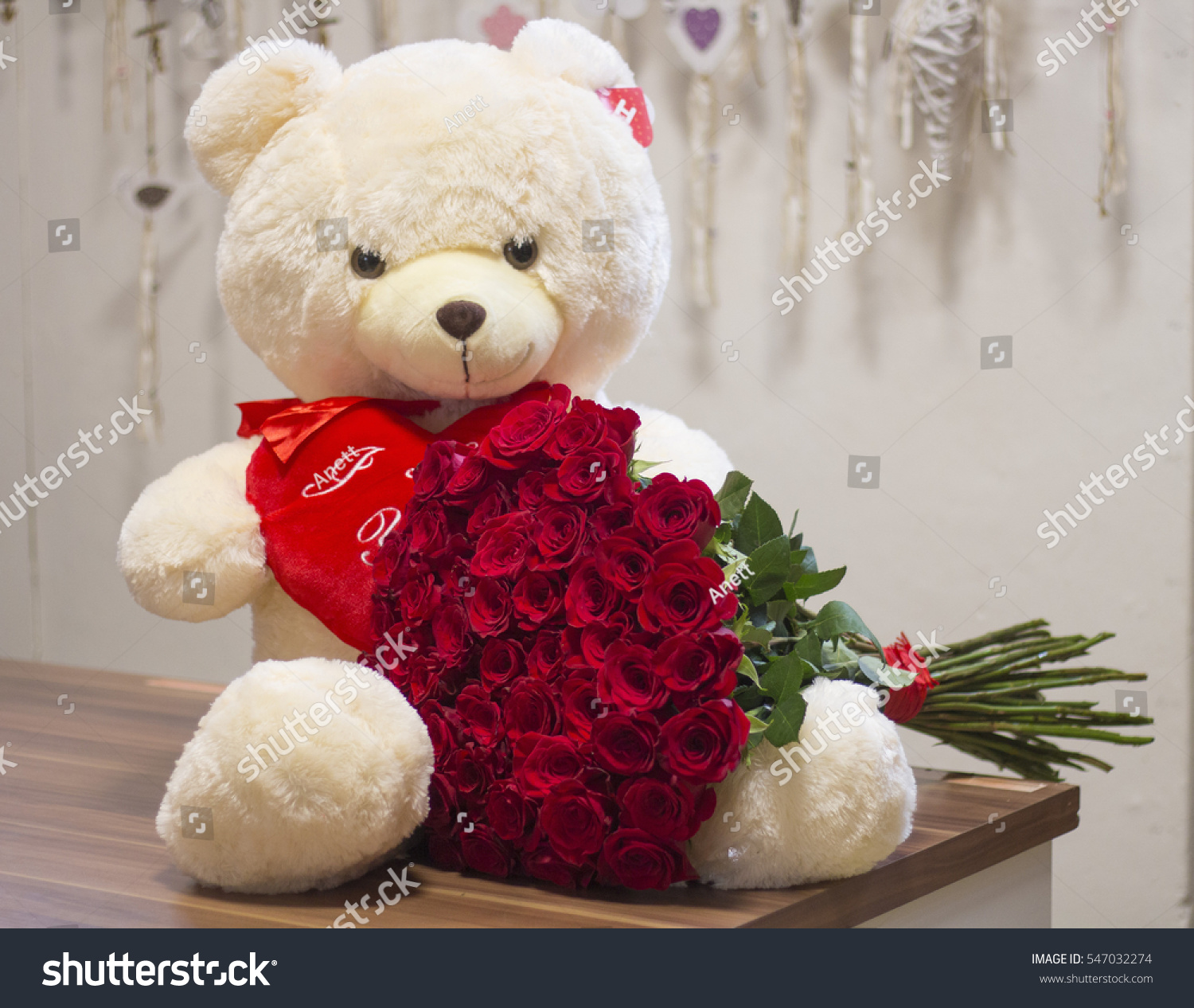 Huge teddy bear is holding an amazing bouquet of a hundred of red roses Huge valentines