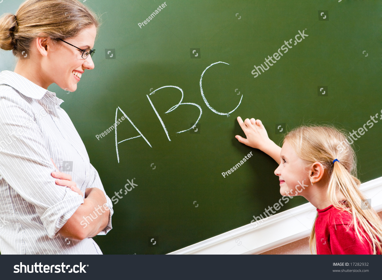 Image Of Smart Girl Pointing At Letter On Blackboard And Looking At Her ...