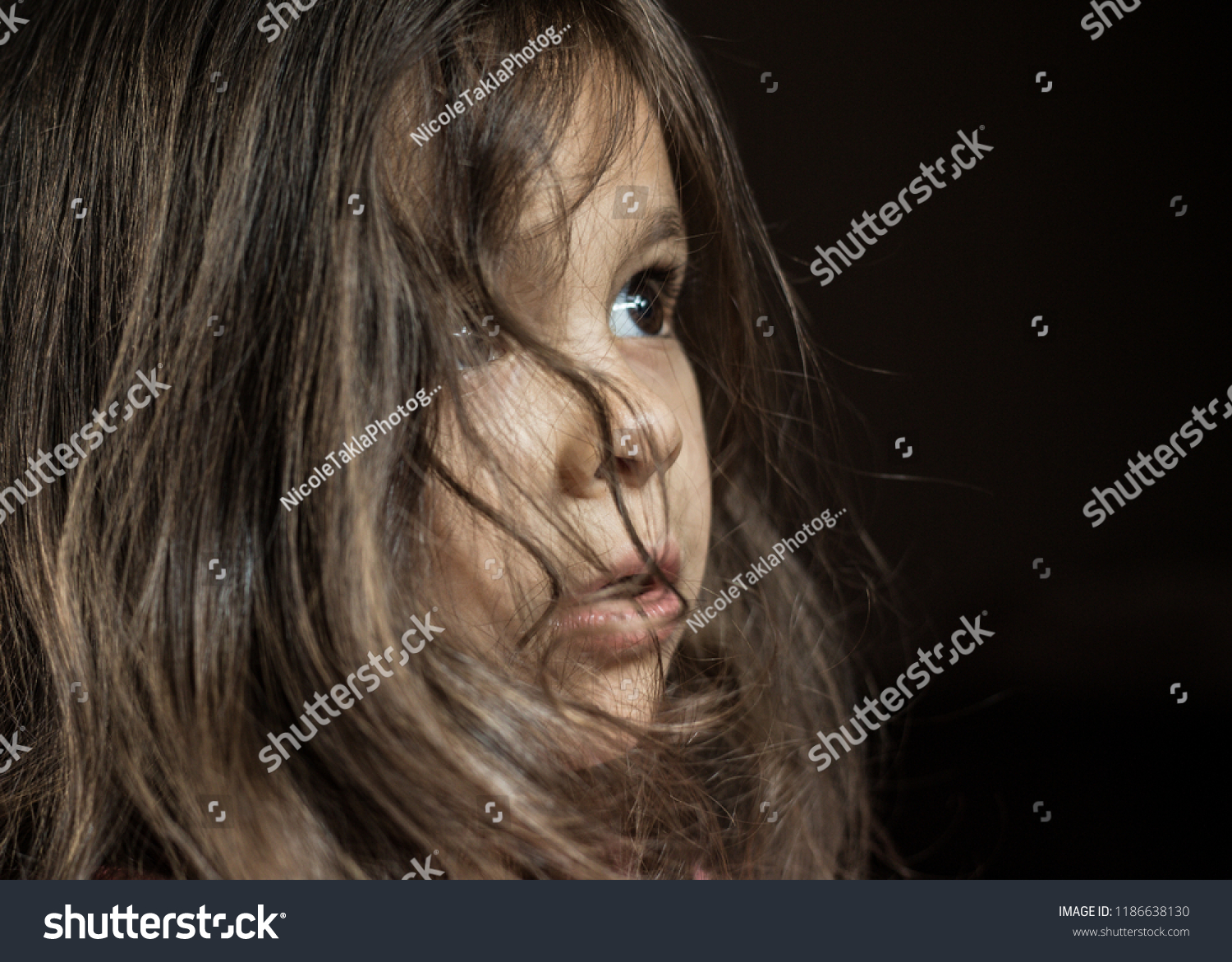 3歳のレバノン人と白人の女の子の横顔を 畏敬と好奇心で少し上向きに見つめながら分離した接写 彼女の茶色い髪は自由に顔の周りに落ちる の写真素材 今すぐ編集