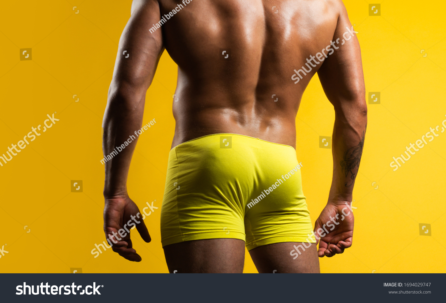 黄色い背景に人の尻 筋肉質の臀部を持つ筋肉質の男性 裸の胴体 裸の雄のロバ の写真素材 今すぐ編集