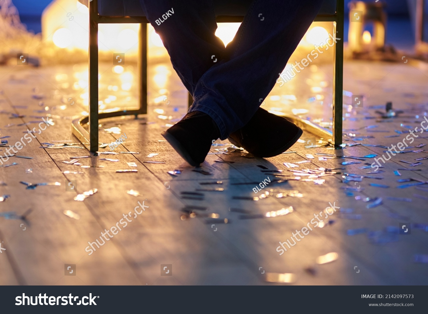 Man Sitting Crosslegged On Chair Closeup Stock Photo 2142097573   Stock Photo Man Sitting Cross Legged On A Chair Closeup Blurred Background 2142097573 