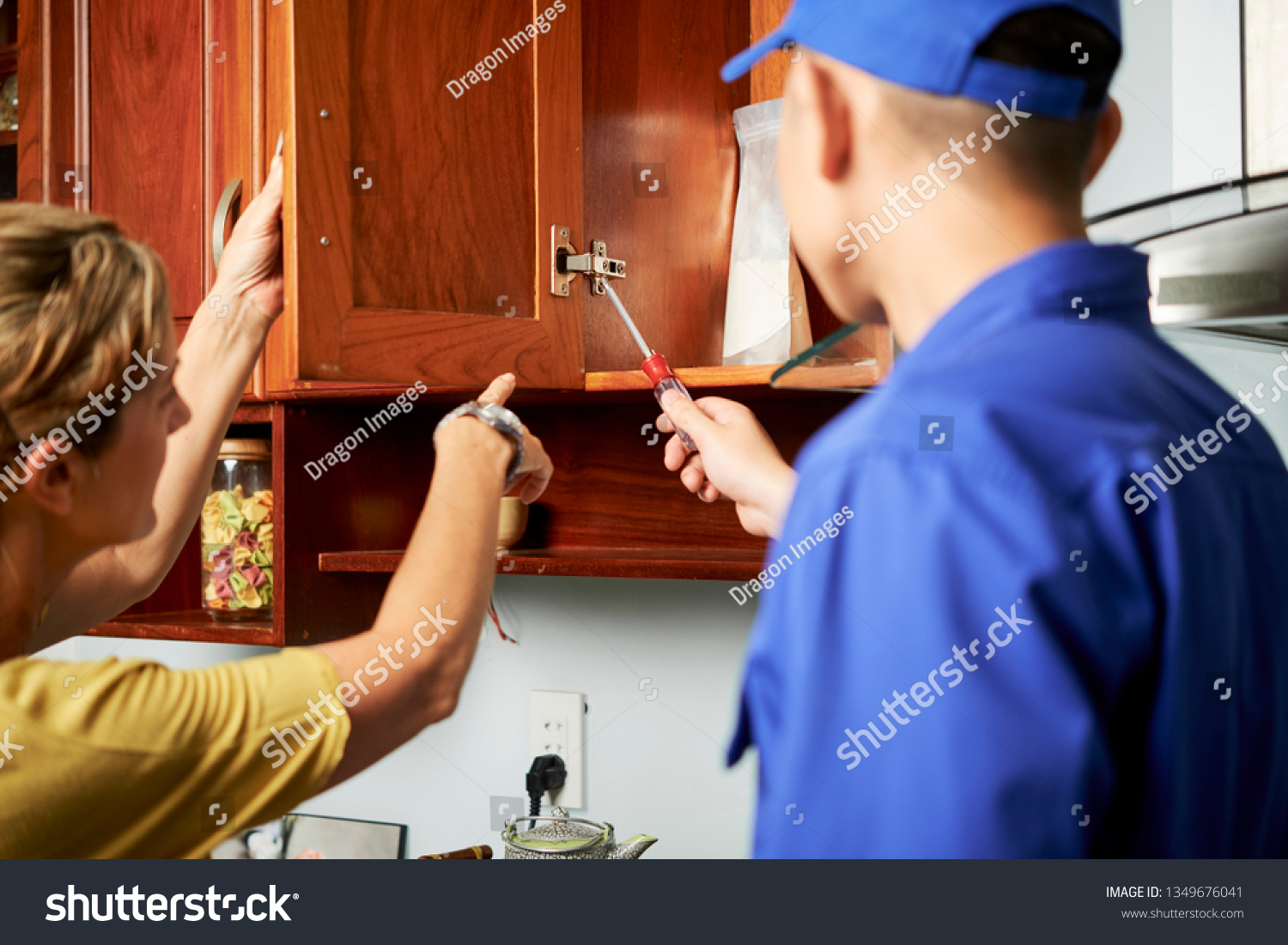Mature Housewife Showing Repairman Broken Cabinet Stock Photo