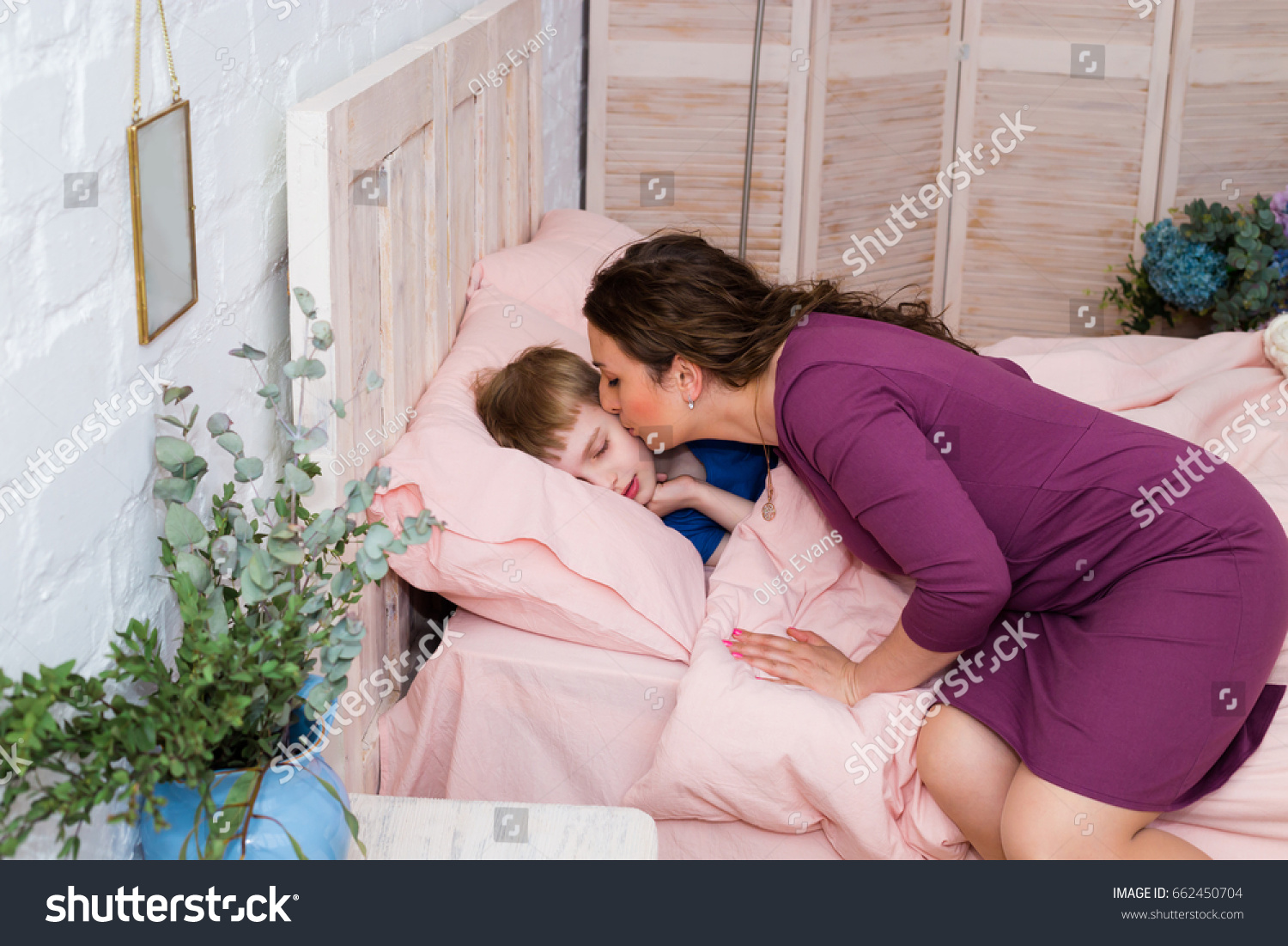 お母さん寝てる息子におやすみのキスを 可愛いお母さんが息子を寝かしつけた お母さんはベッドで赤ちゃんにキスをしている 寝室で寝ているお母さんと子ども の写真素材 今すぐ編集
