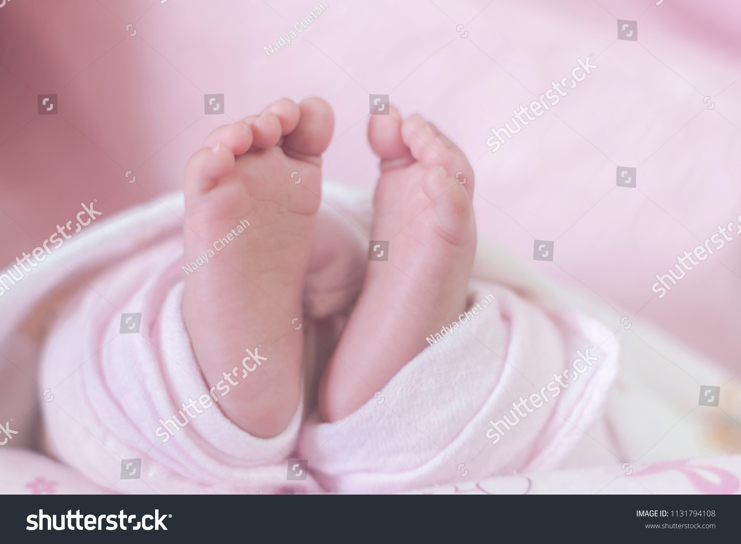 Newborn baby on a pink blanket tiny baby feet closeup happy family concept
