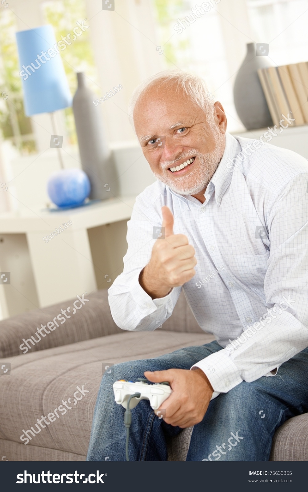 stock-photo-older-man-sitting-on-couch-giving-thumb-up-while-playing-computer-game-looking-at-camera-smiling-75633355.jpg