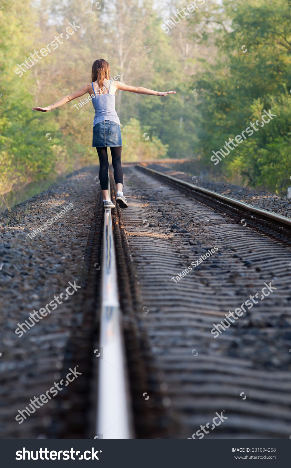 One Teen Girl Balancing Away On Rail At Sunset With Trees Behind Her ...