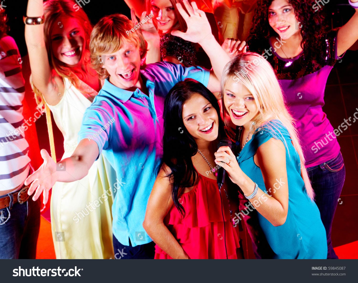 Photo Of Pretty Girls Singing In Mic At Party With Their Friends Behind ...