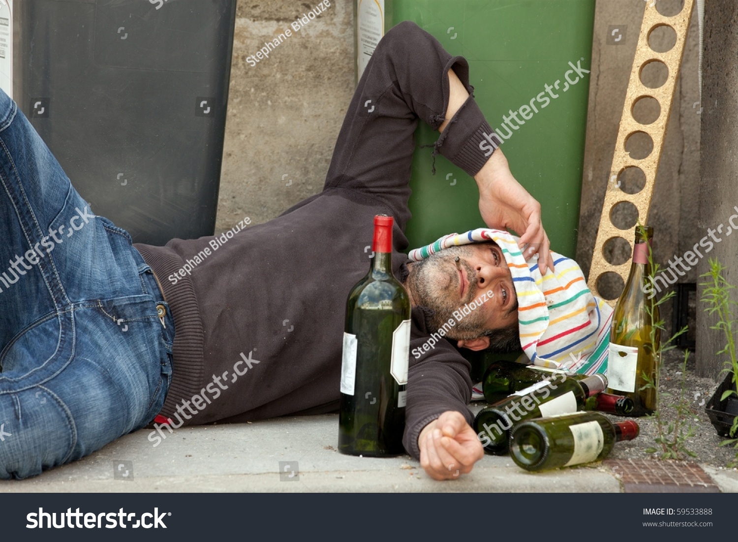 Poor And Drunk Man Lying On Sidewalk With Bottles Of Wine Near Trash ...