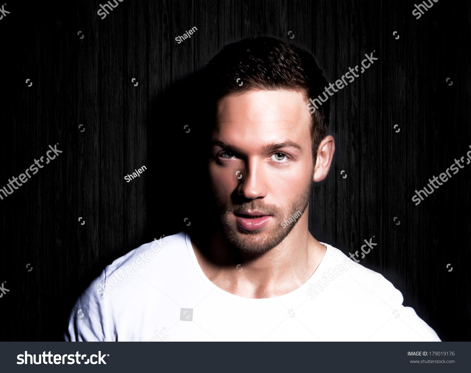 portrait-of-young-good-looking-man-staring-at-viewer-against-black