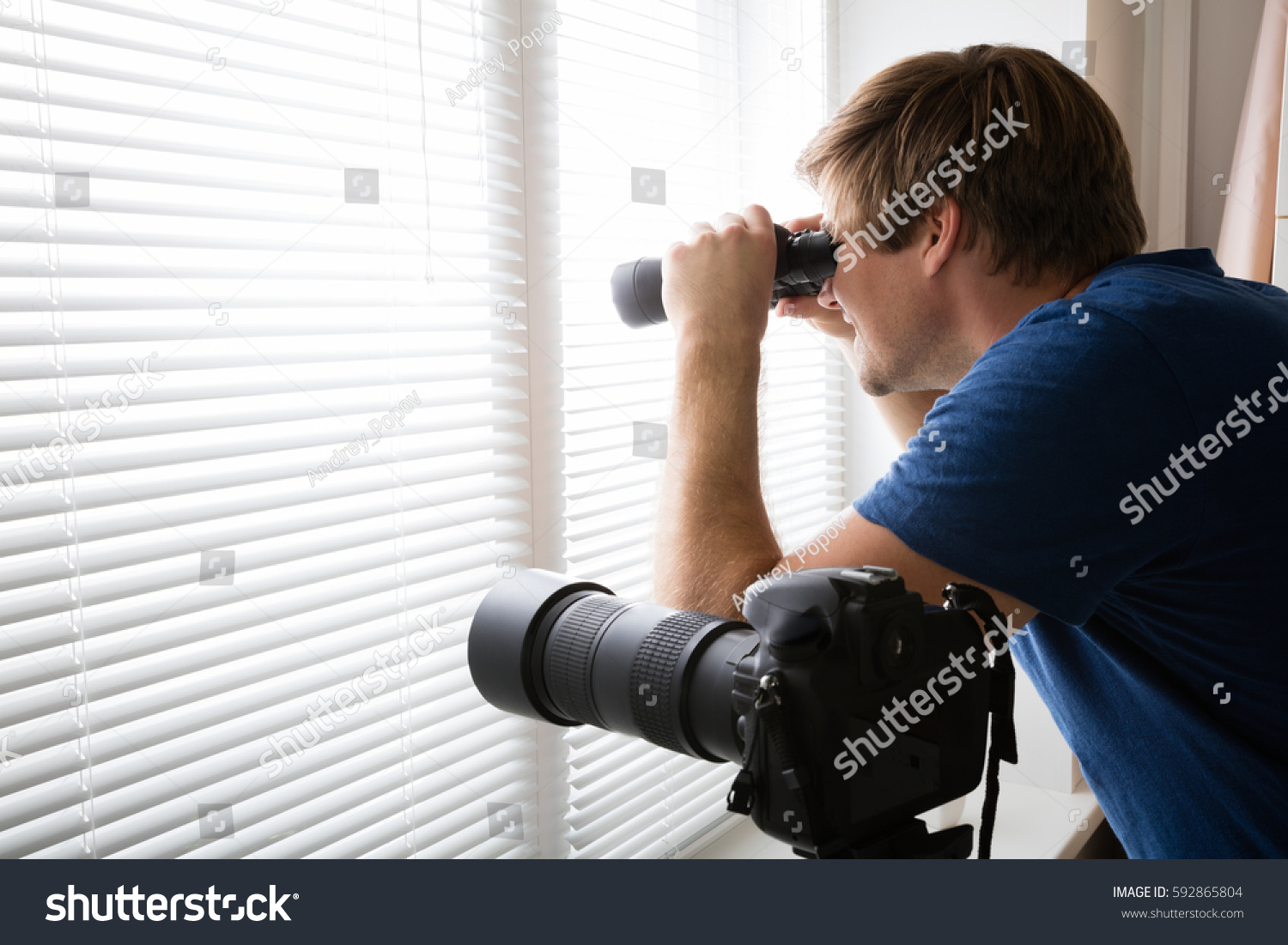 stock-photo-private-detective-spying-with-binoculars-looking-through-blinds-near-slr-camera-592865804.jpg