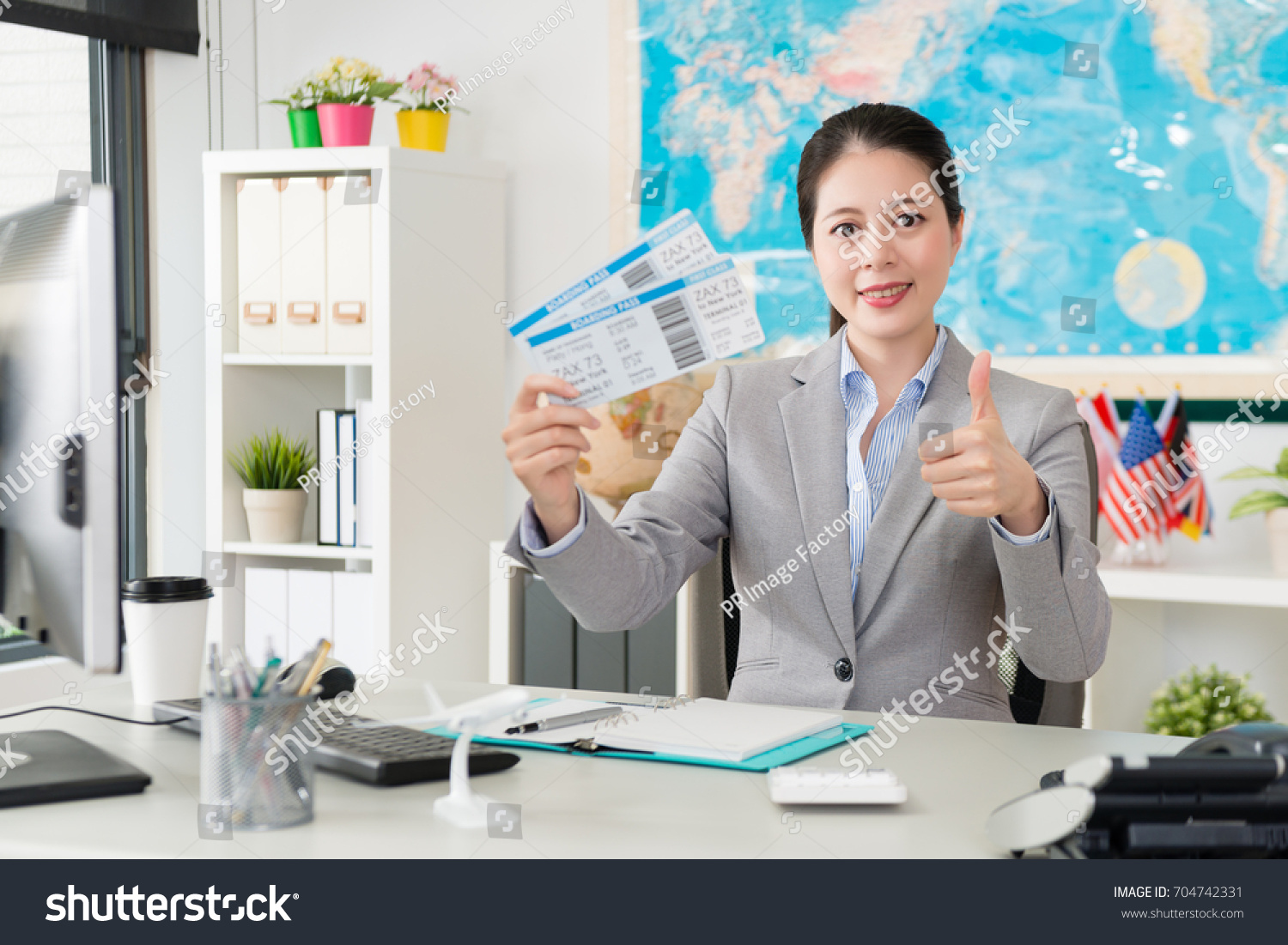 Professional Young Female Travel Agent Office Worker Holding Airline Tickets Face To Camera And Showing Thumb Professional Young Female Travel Agent Office Worker Holding Airline Tickets Face To Camera And Showing Thumb