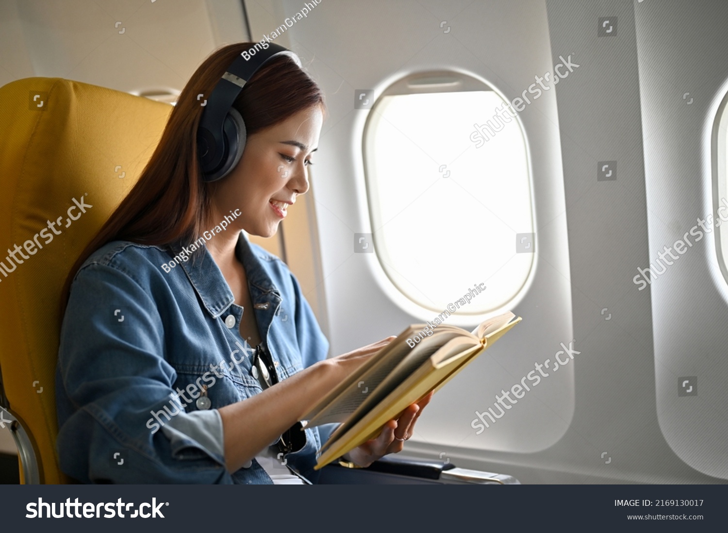 relaxed-millennial-asian-travel-on-plane-stock-photo-2169130017