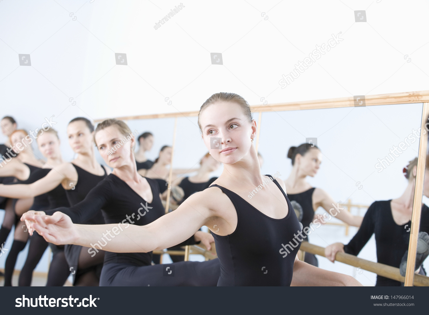 Row Of Female Ballet Dancers Practicing At Barre In Rehearsal Room ...