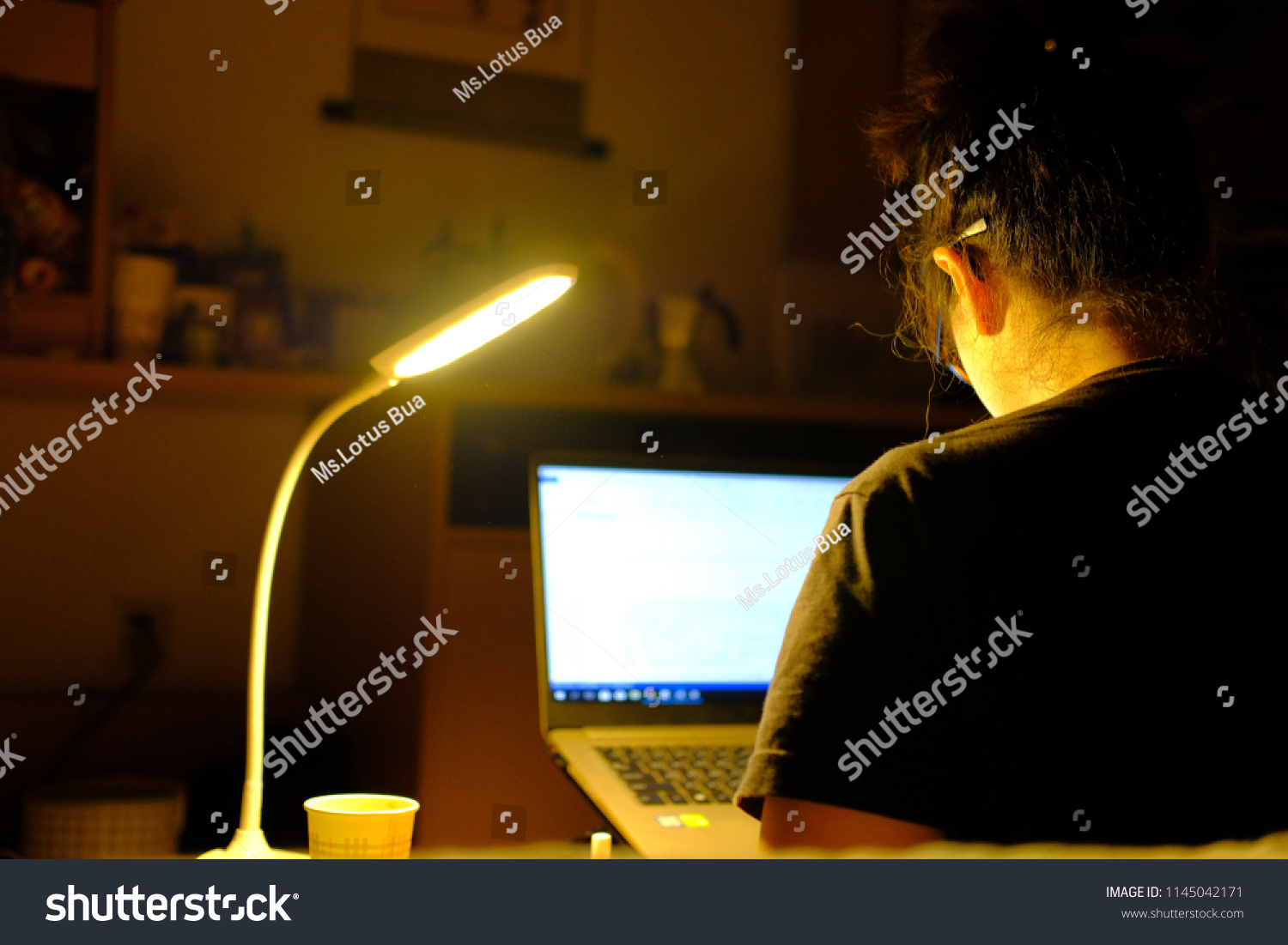 アジアの若い学生が 自分の部屋で勉強したり書いたりするために コンピューターを使って眼鏡をかけたりすることに 限定的にフォーカス 暗い部屋 で夜働く の写真素材 今すぐ編集