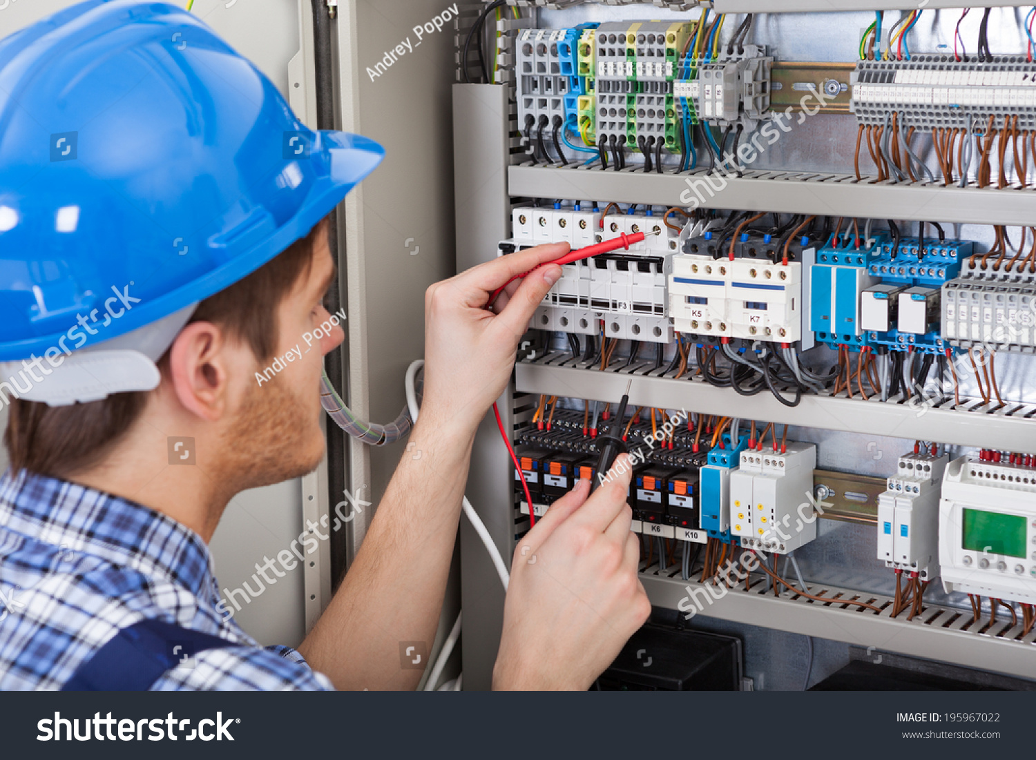 Side view of male technician examining fusebox with multimeter probe