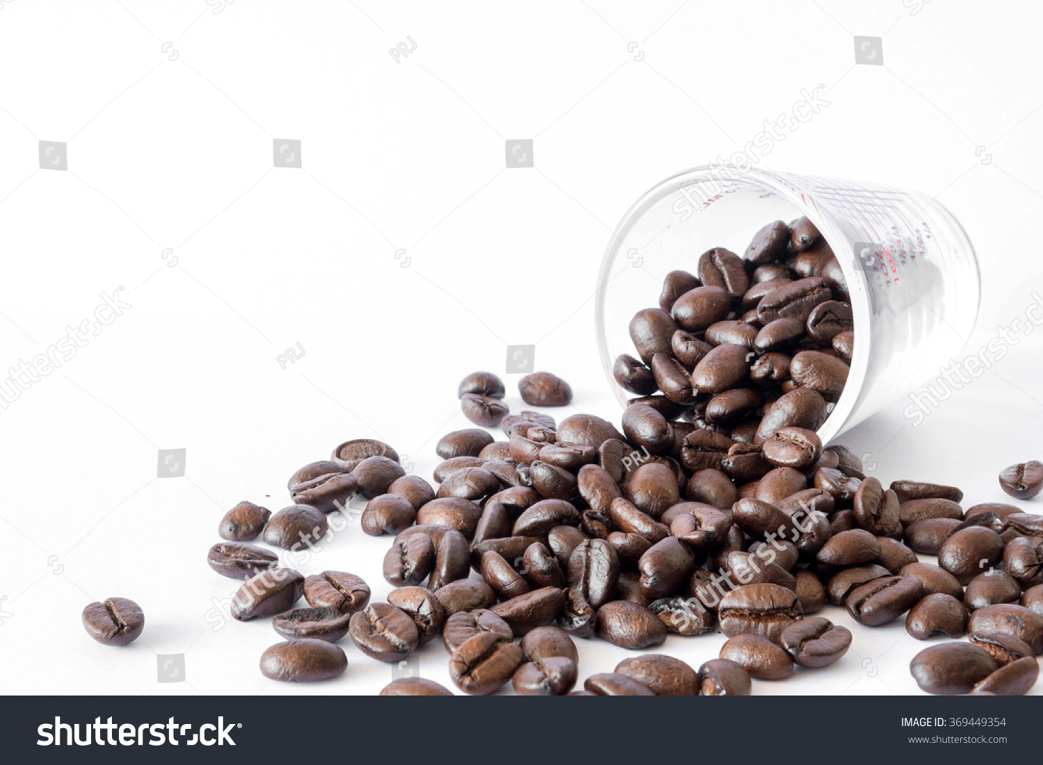 Spilled Coffee Beans From The Transparent Cup Isolated Over White Background Spilled Coffee Beans From The Transparent Cup Isolated Over White Background