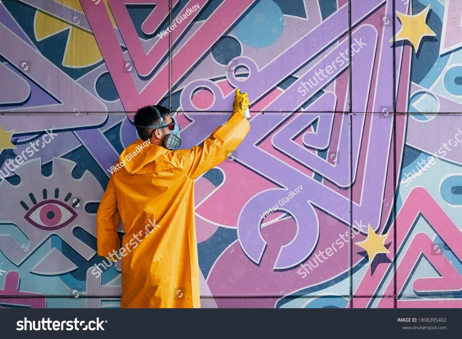 street-artist-painting-colorful-graffiti-on-stock-photo-1898395402