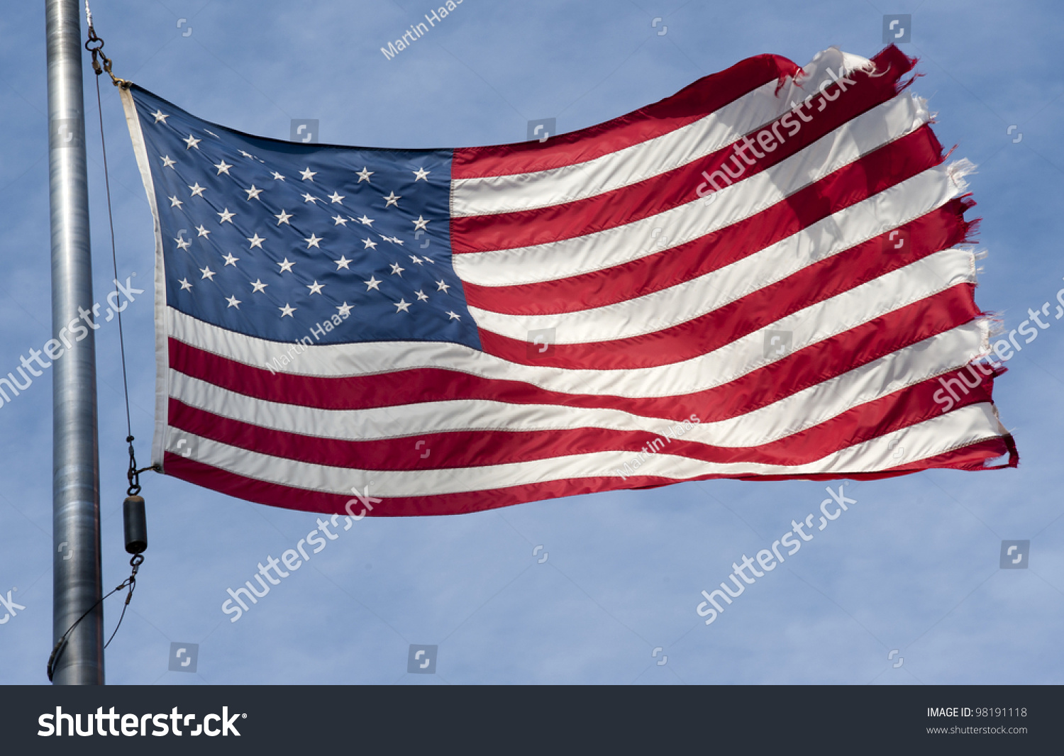 Tattered American Flag Flapping In The Wind On A Blue Sky With Clouds ...