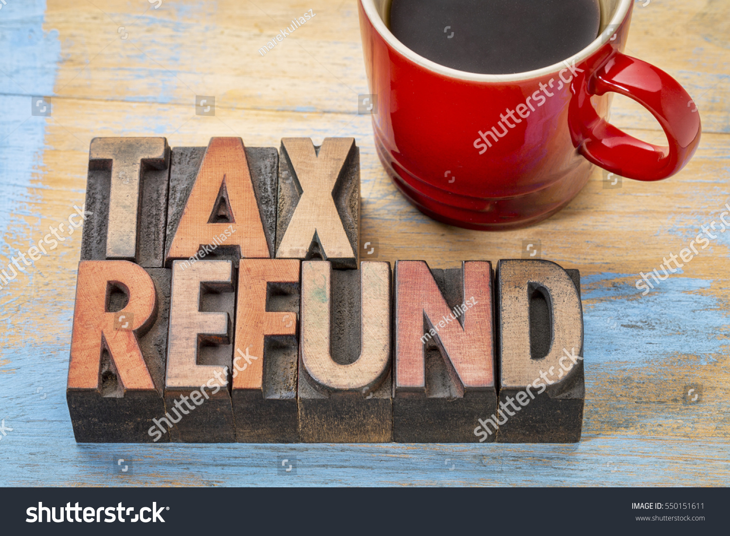 The word tax refund is written in wooden letterpress type next to a cup of coffee.