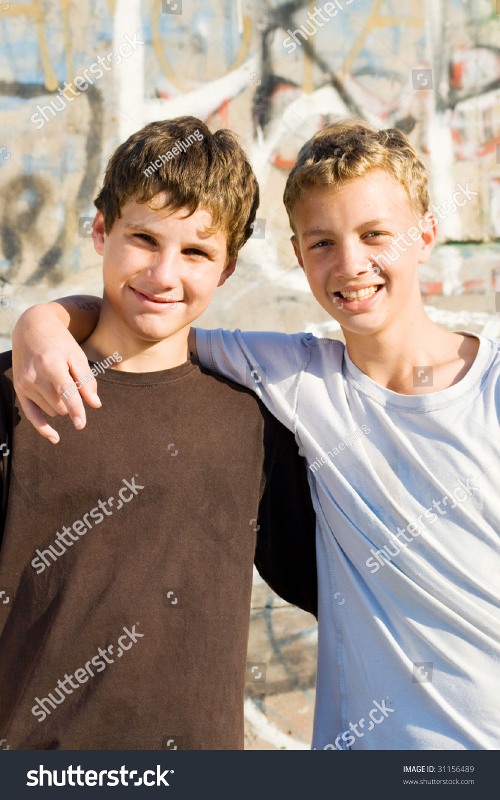Two teenage boys walking barefoot through a forest with 