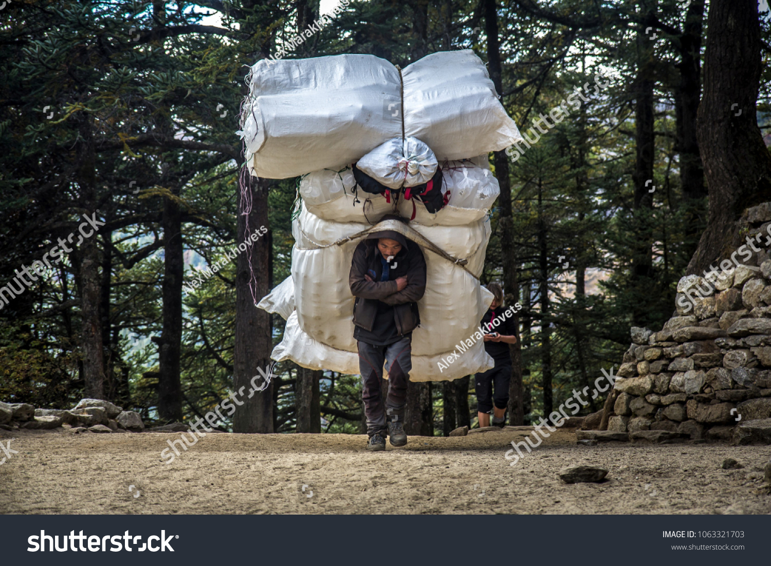 stock-photo-tengboche-nepal-november-porter-with-extremely-heavy-load-walks-along-the-path-on-his-1063321703.jpg