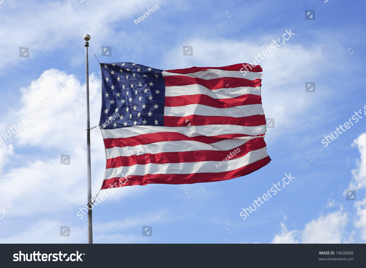 The American Flag Flapping In A Strong Wind Against A Blue Sky With ...