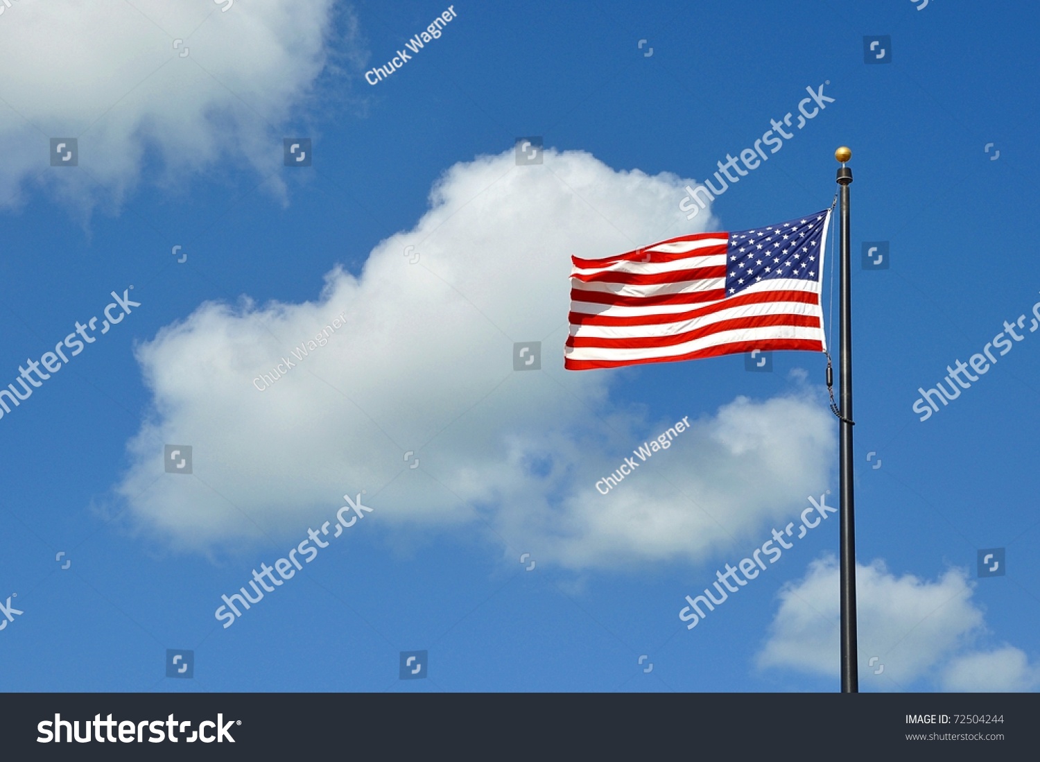 The American Flag Flying Against A Blue Sky With White Clouds On A ...