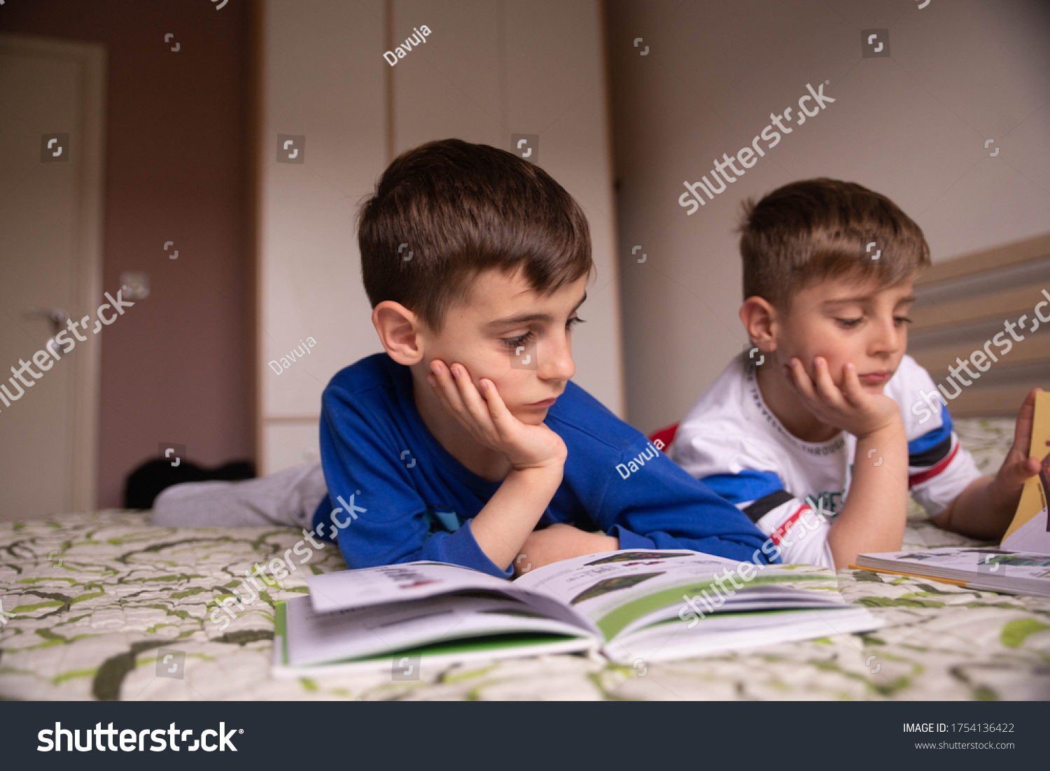 boys-lying-on-bed-reading-books-stock-photo-1754136422-shutterstock